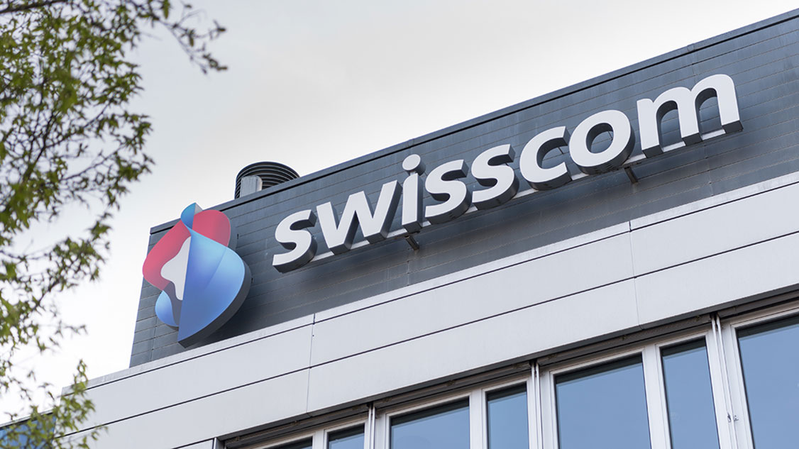The picture shows part of the Swisscom building in Worblaufen with the Swisscom logo.