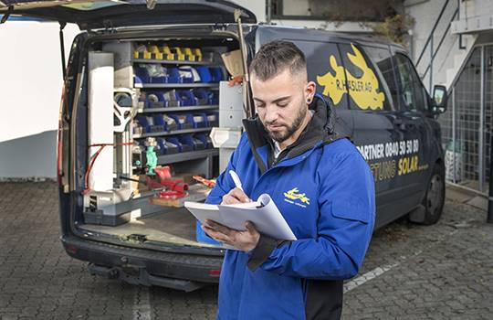 Un addetto al servizio di montaggio del gruppo Häsler scrive la durata del suo lavoro davanti al suo furgone nel registro.