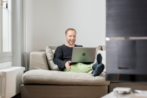 Mann mit Laptop auf Sofa